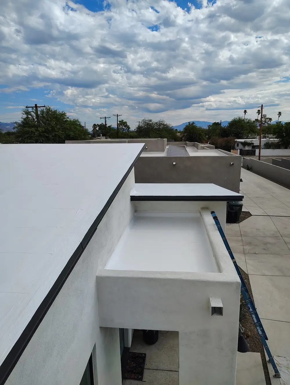 White coated low-sloped roof on a Tucson home under monsoon clouds