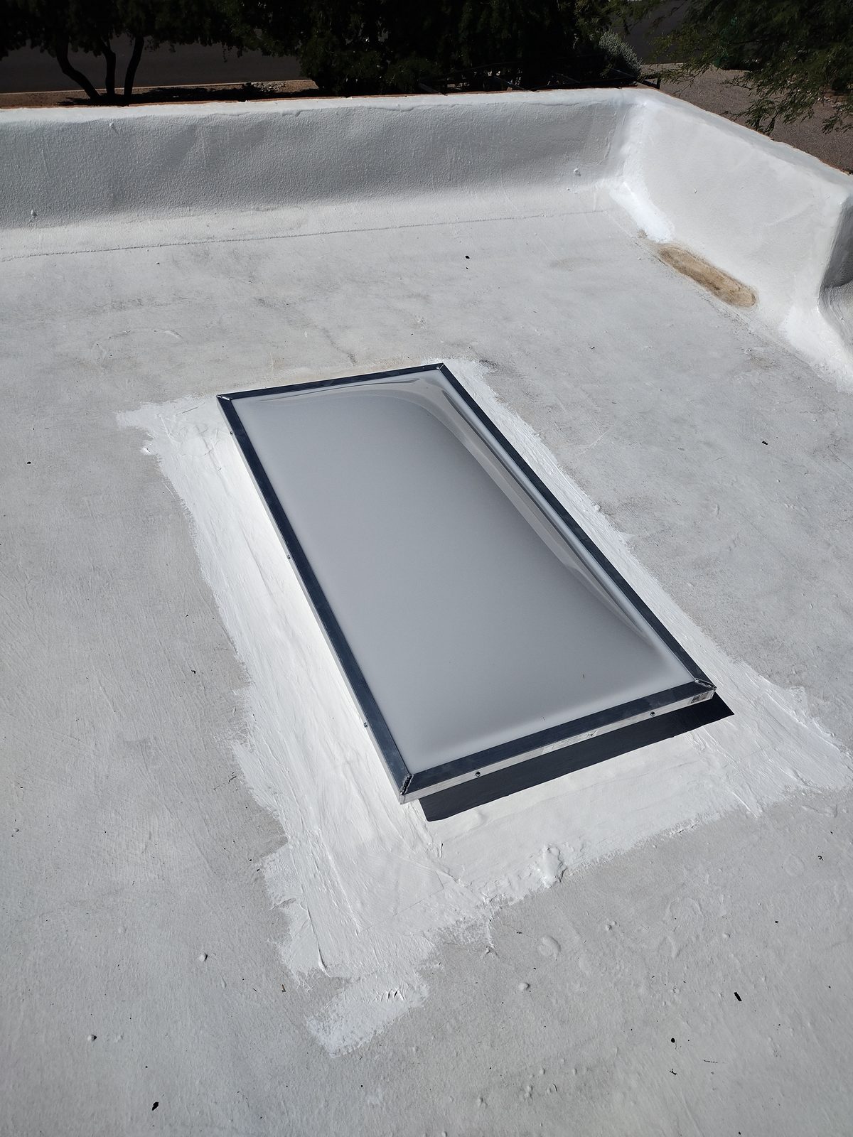 New skylight dome installed and sealed into a coated flat roof in Tucson