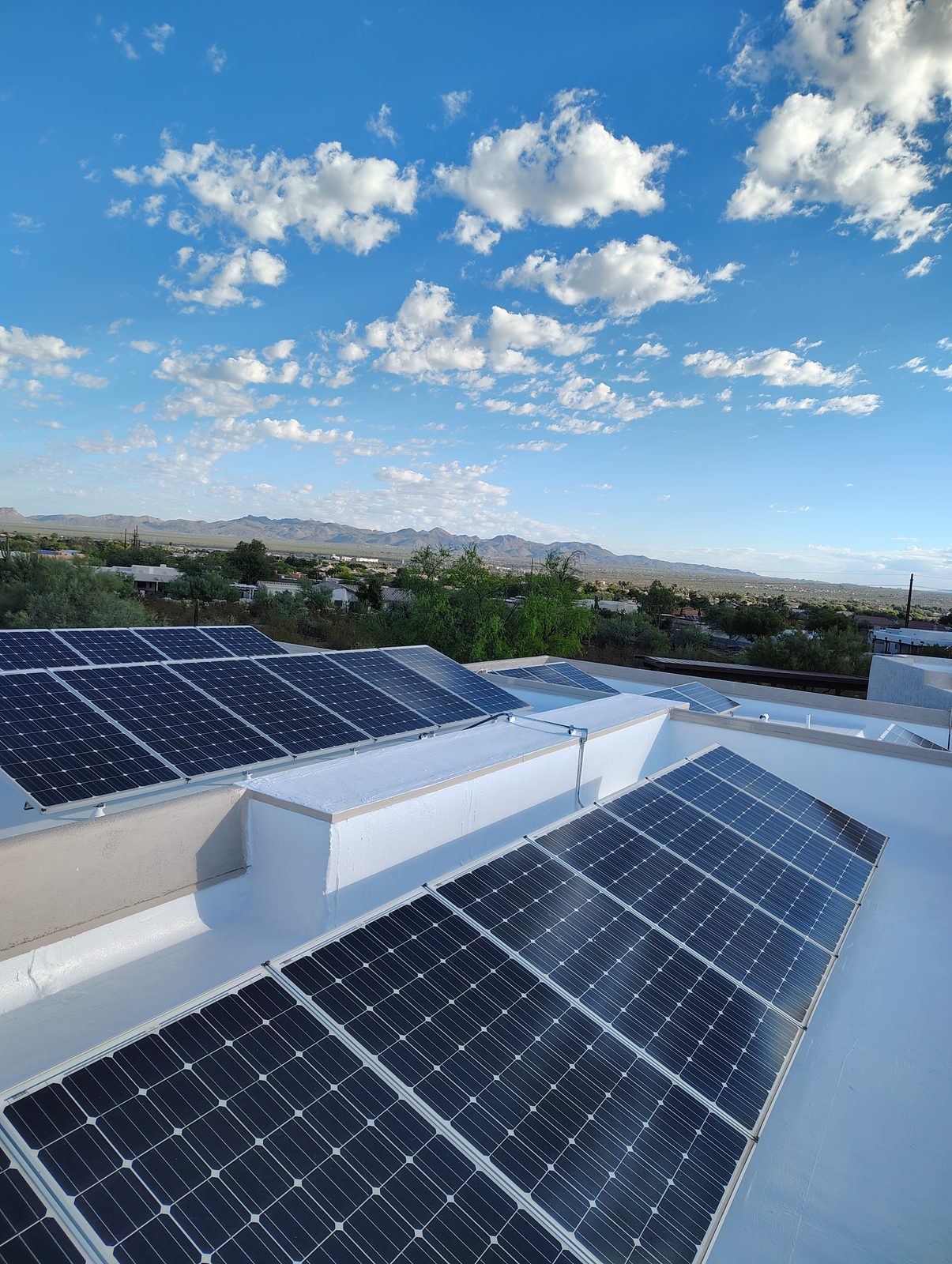Solar panels mounted over a freshly coated white flat roof in Tucson