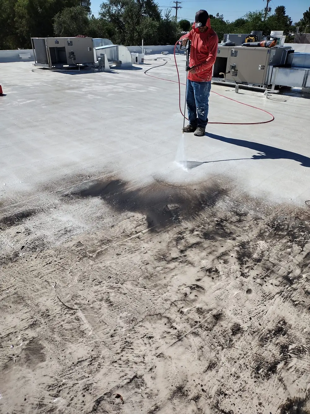 Pressure washing a Tucson roof, showing the cleaned surface next to the untouched section