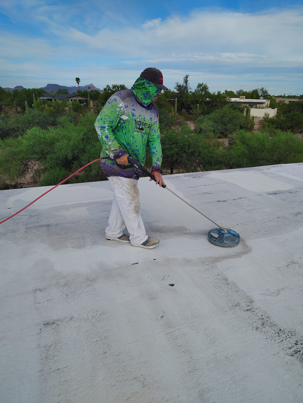 Pro Roof LLC crew member power scrubbing a flat roof in Tucson before coating