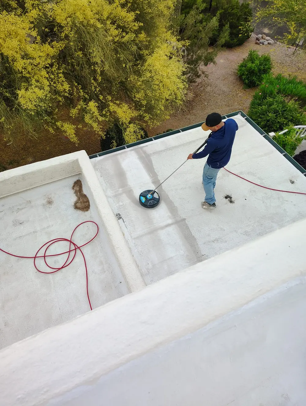 Pro Roof LLC crew member power scrubbing a low-sloped Tucson roof before coating