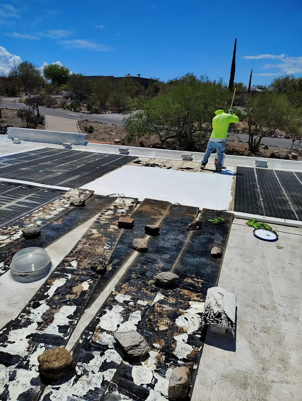 Crew member applying coating during maintenance work on a larger Tucson roof