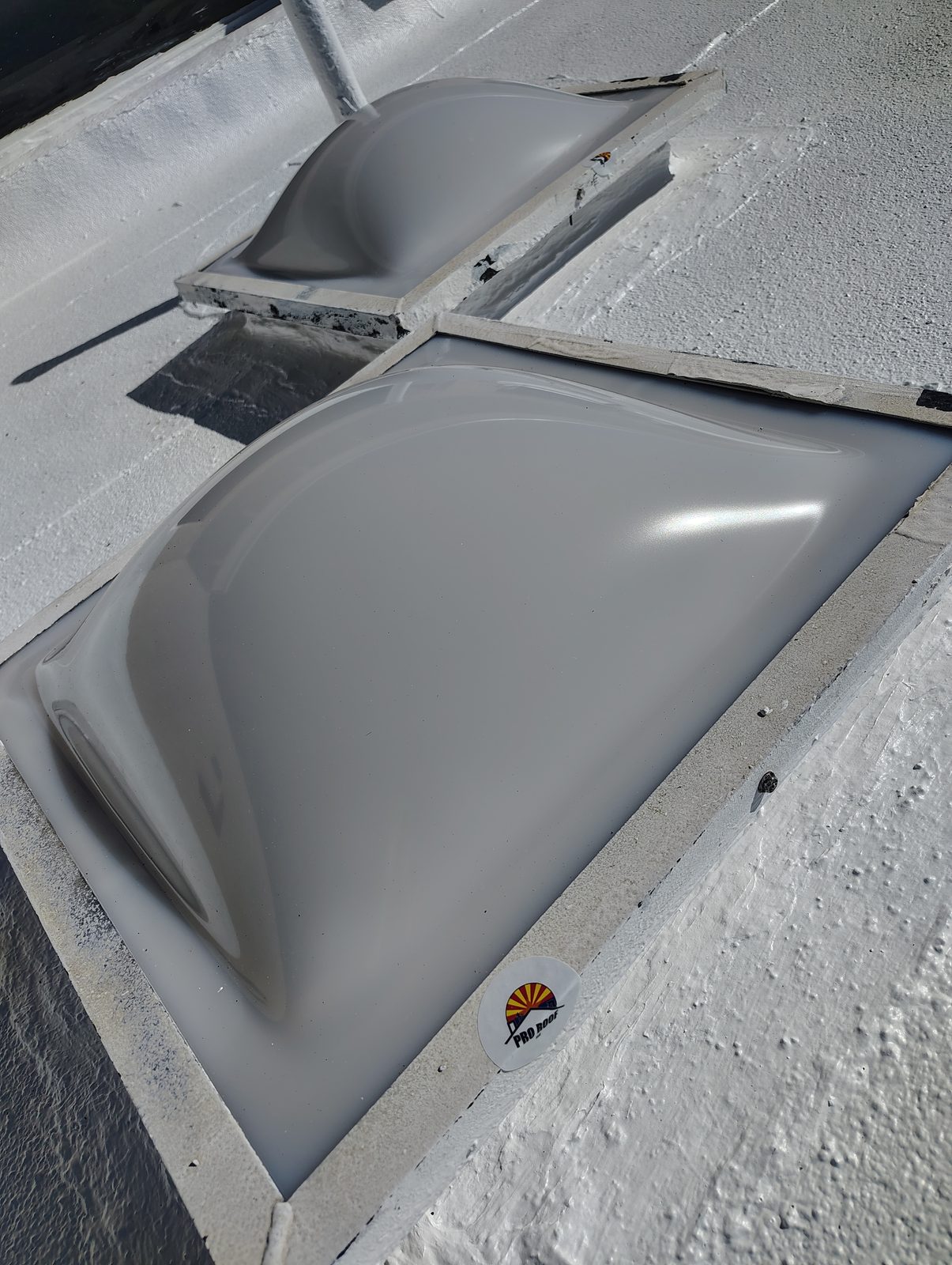 New acrylic skylight dome sealed into a coated flat roof in Tucson