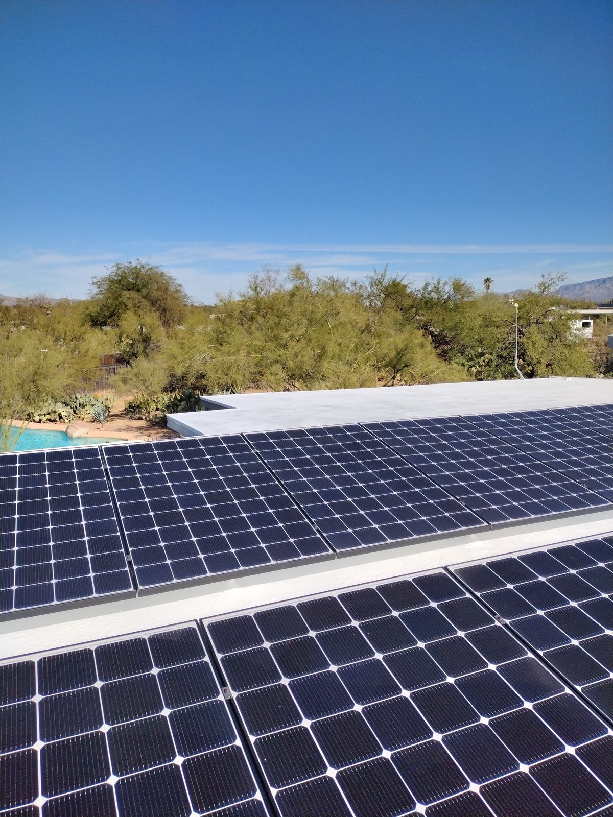 Solar panel array on a coated flat roof with desert landscaping in greater Tucson