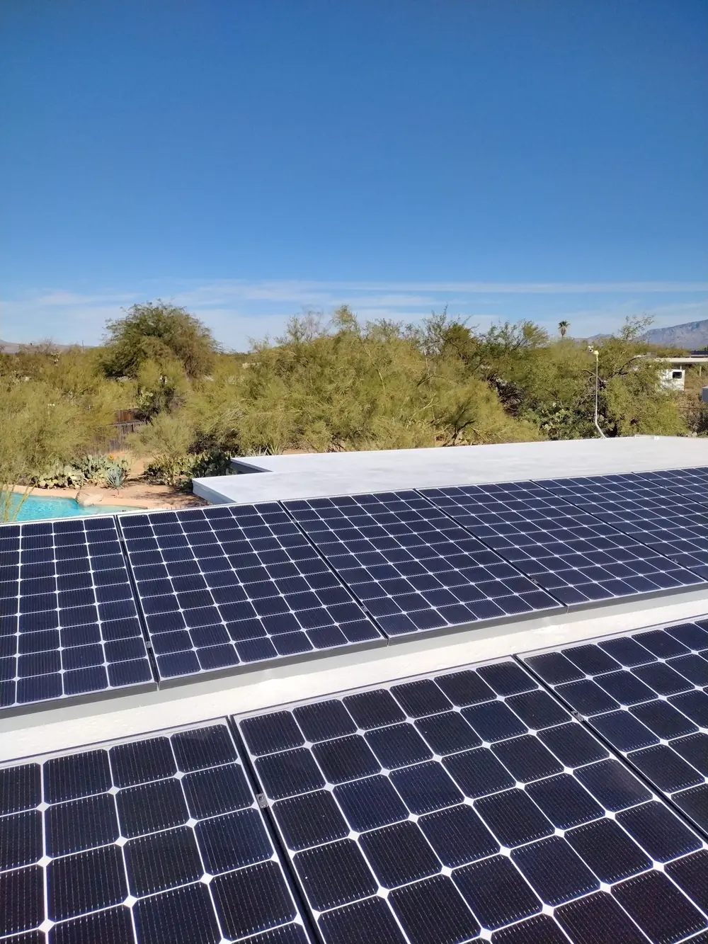 Solar panel array on a coated flat roof in Oro Valley with desert landscaping