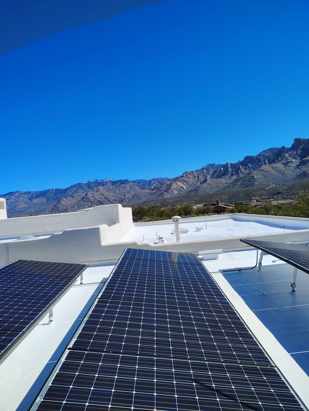 Solar panels on a freshly coated flat roof with the Santa Catalina Mountains behind, Tucson